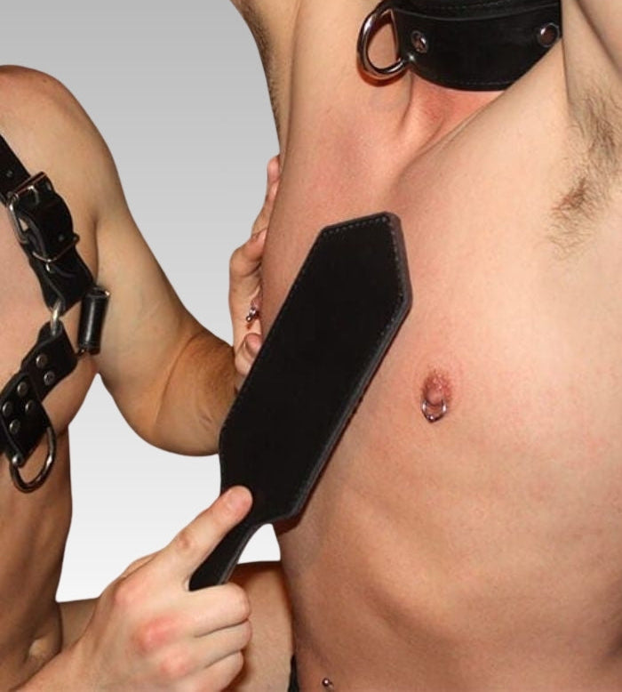 Mini black leather paddle showing its flat blade beside the model's upper body