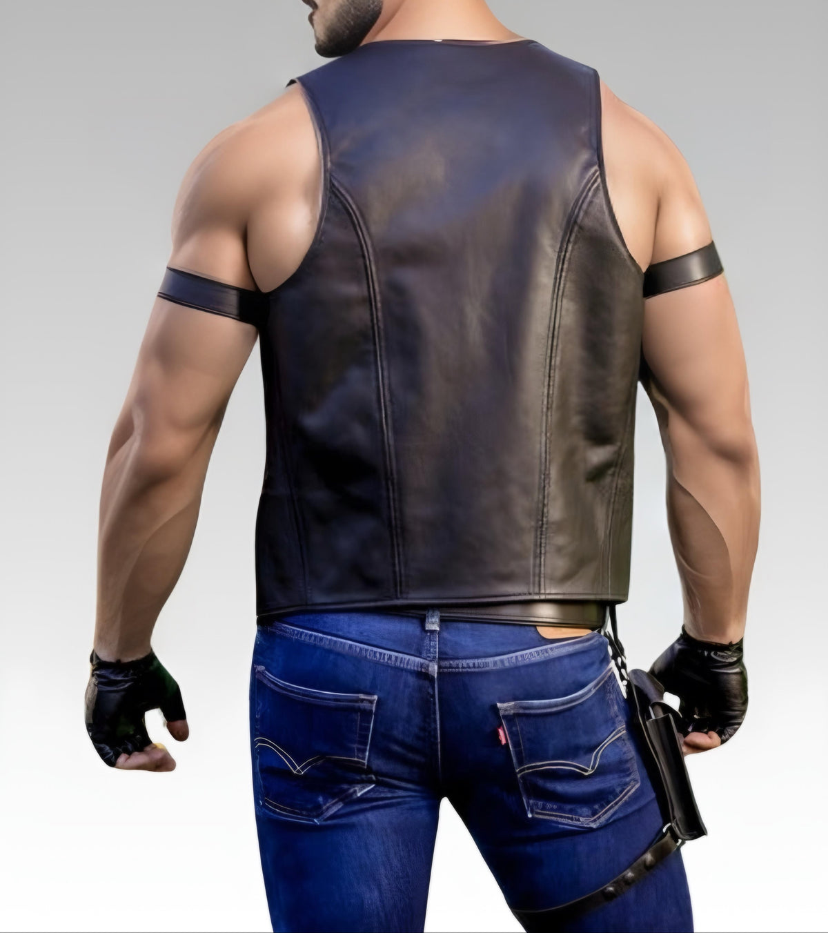 Man wearing a leather vest and blue jeans on a gray background