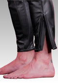 Close-up of black leather pants with a gray background